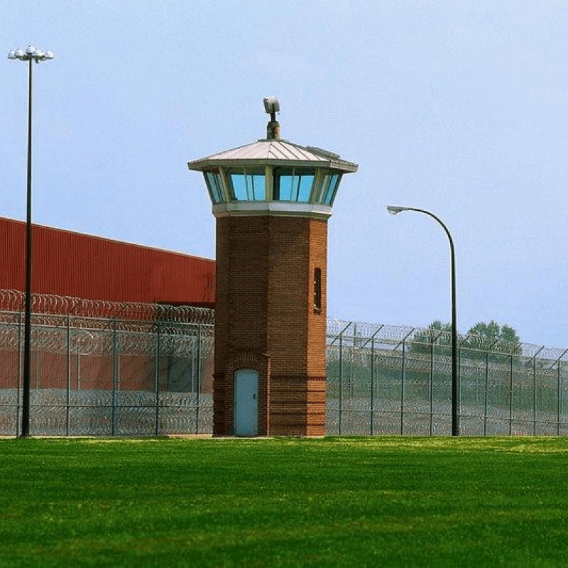 Watchtower with spotlight next to barbed-wire fence